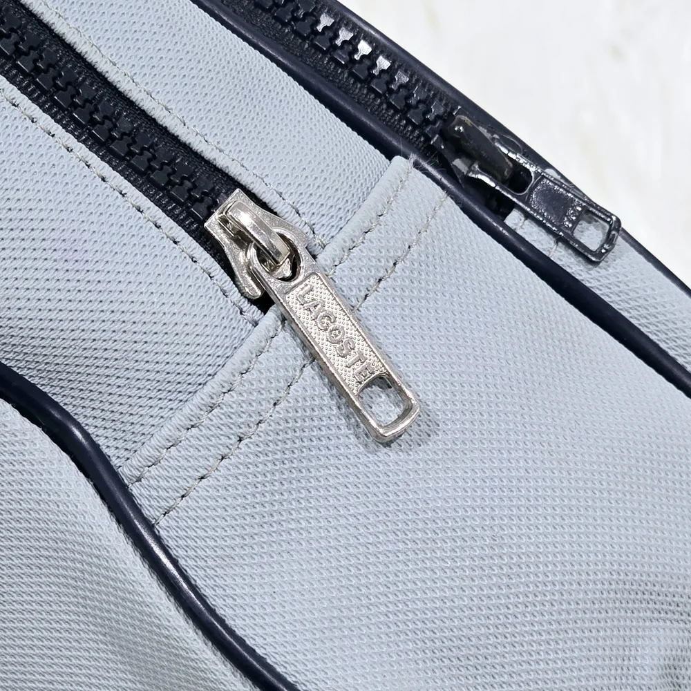 Lacoste mini backpack in a soft light blue shade with navy blue trim accents.